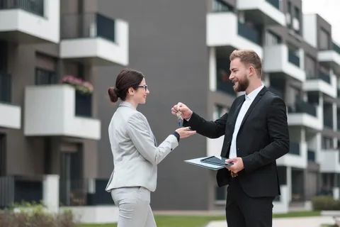 Real estate agent handing property keys to a client outside an apartment building.