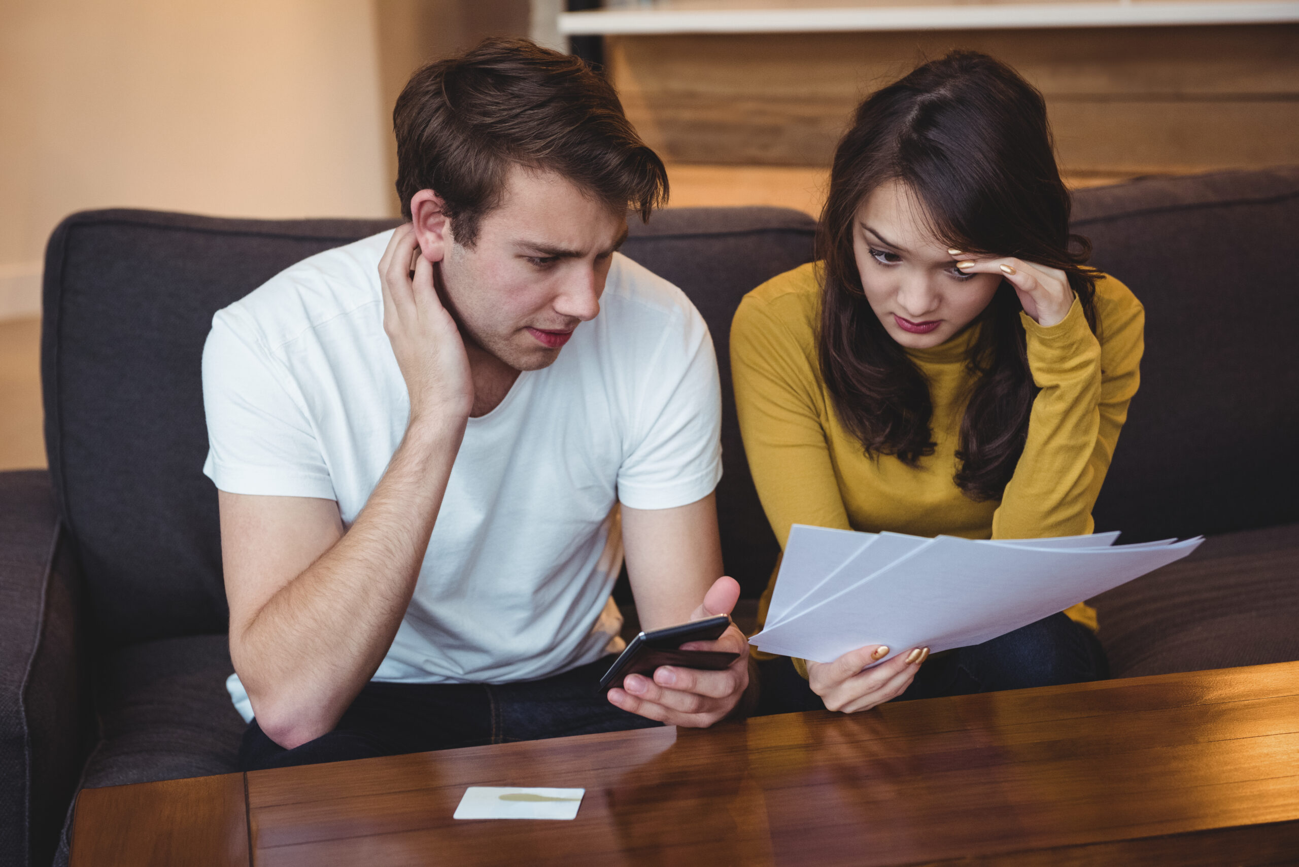 Couple discussing financial documents related to commercial lease penalties at home.