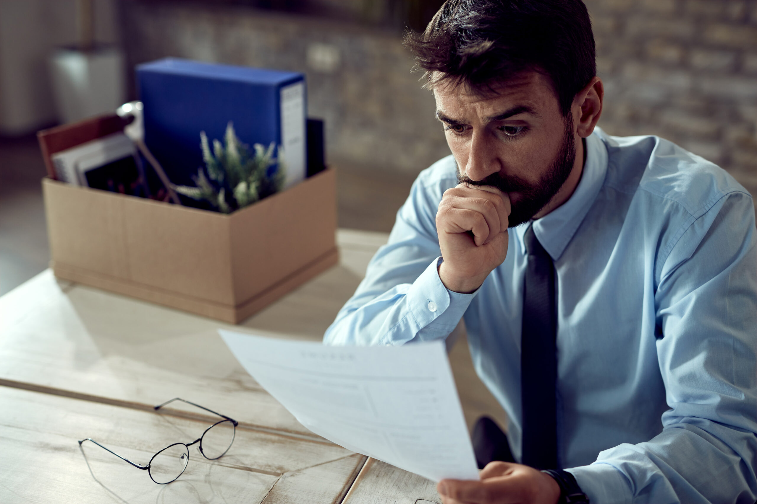 A stressed businessman going through office paperwork to prevent costly contract mistakes.