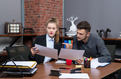 Two office employees reviewing documents and discussing business issue at desk