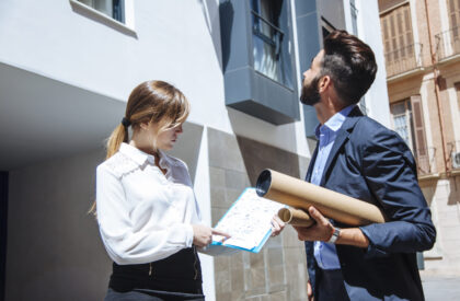 Real estate agents reviewing property plans outside modern residential building