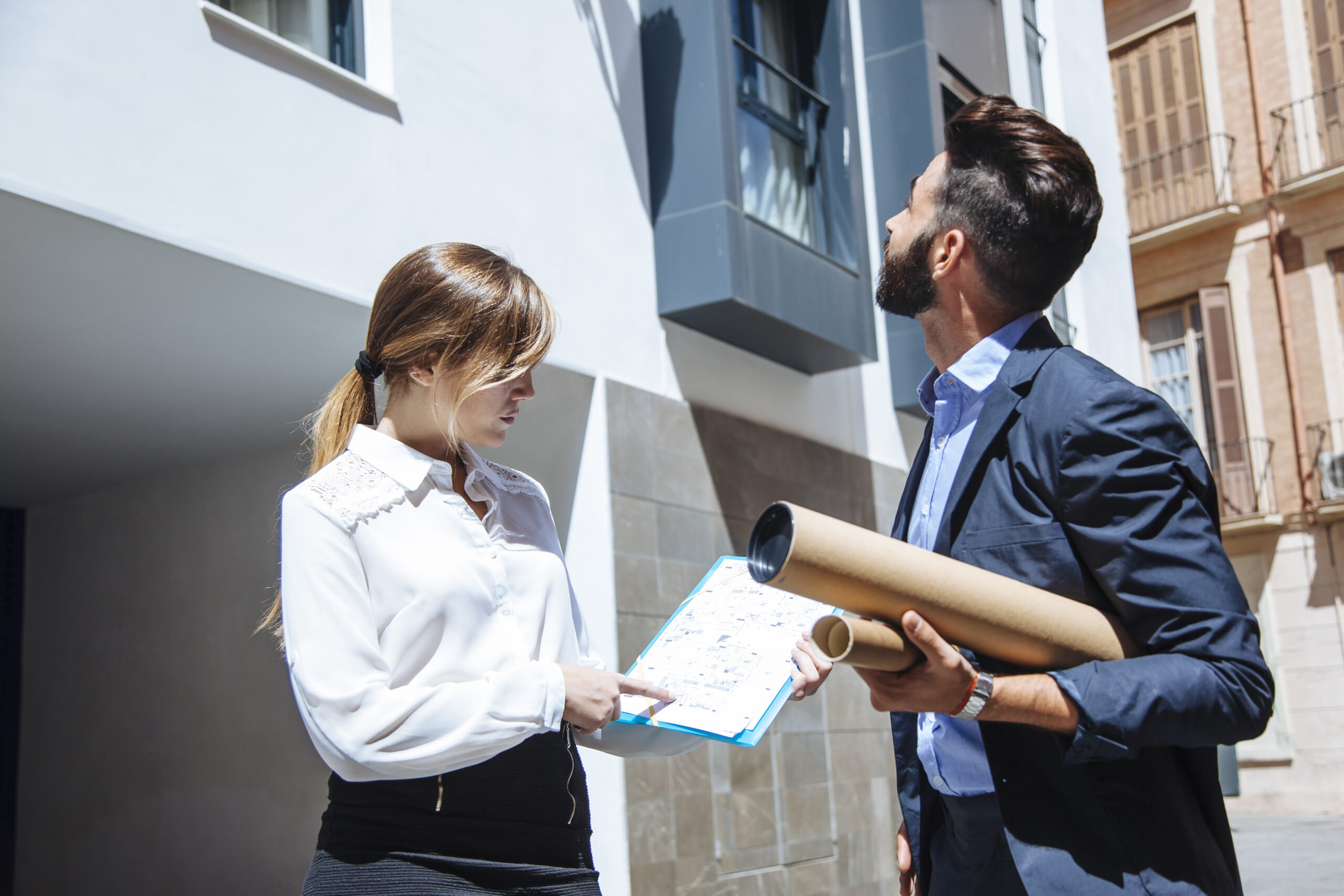 Real estate agents reviewing property plans outside modern residential building