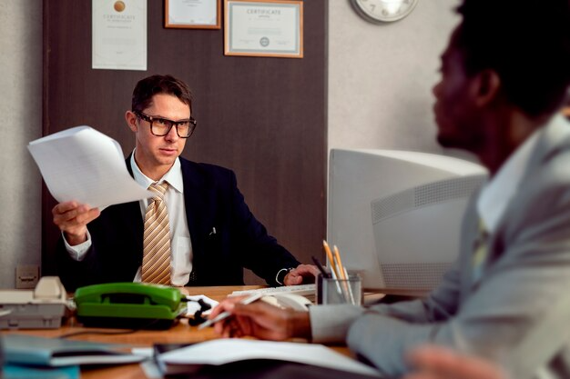 Professional office setting with legal experts reviewing contract documents at vintage desk workspace