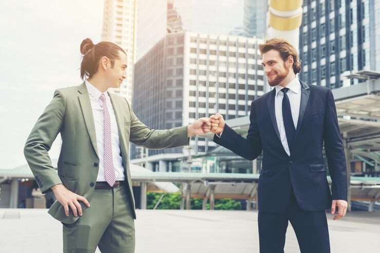 Two professional businessmen celebration high-five fist bump in urban city setting