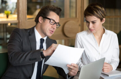Businessman consulting with female colleague on contract conditi A professional lawyer in a suit and glasses explaining property contract conditions to a female client during a legal consultation.
