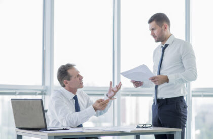 modern-office-composition-with-businessman Businessmen reviewing disputed paperwork during a breach of contract disagreement in a high-rise office setting.