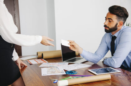 Real estate agent handing a business card to a client during a commercial property lease consultation.
