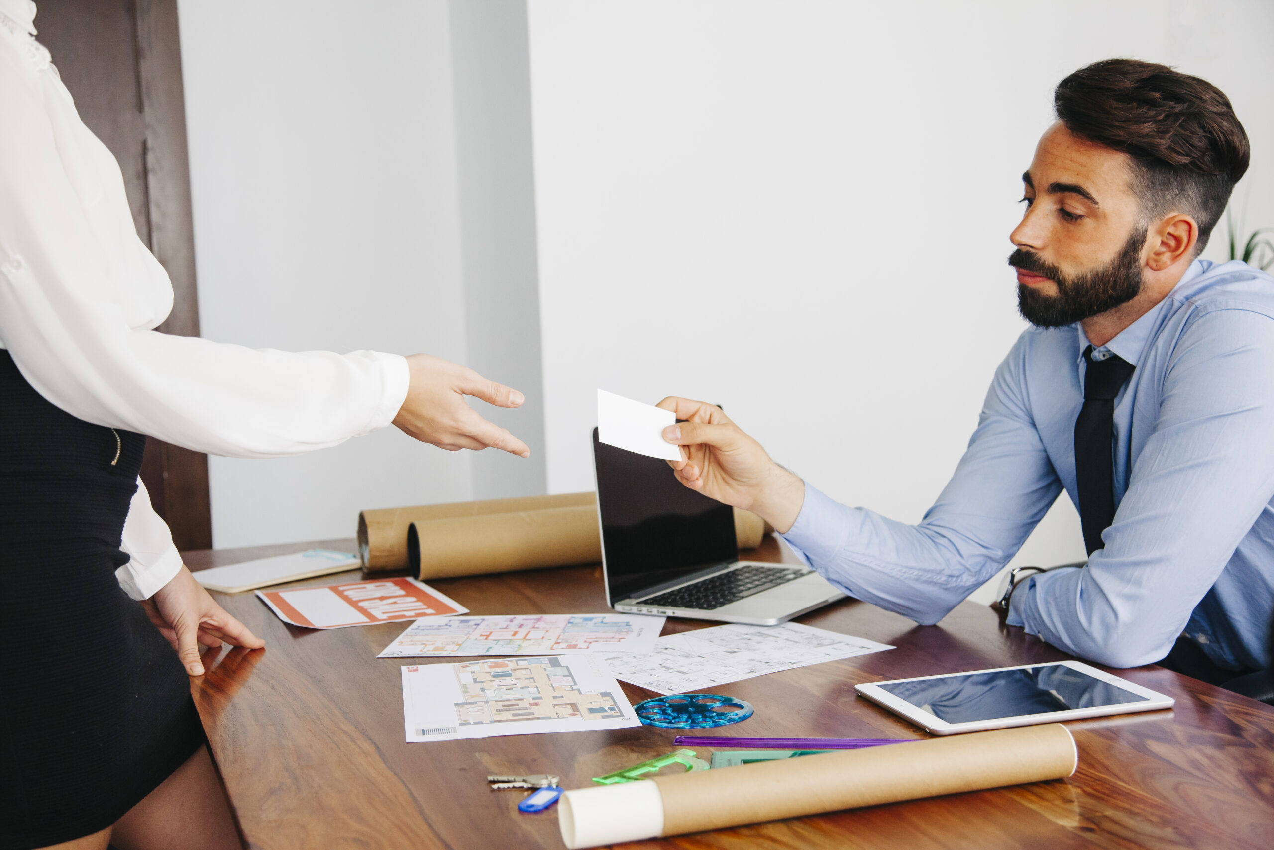 Real estate agent handing a business card to a client during a commercial property lease consultation.