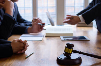 3 Attorney consulting with clients during a legal meeting with a judge's gavel, documents, and digital devices on the conference table.