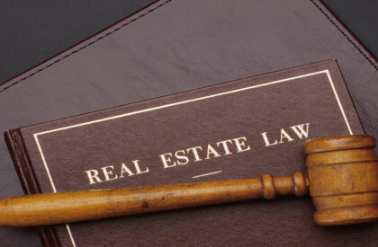 Wooden gavel resting on a leather-bound Real Estate Law book