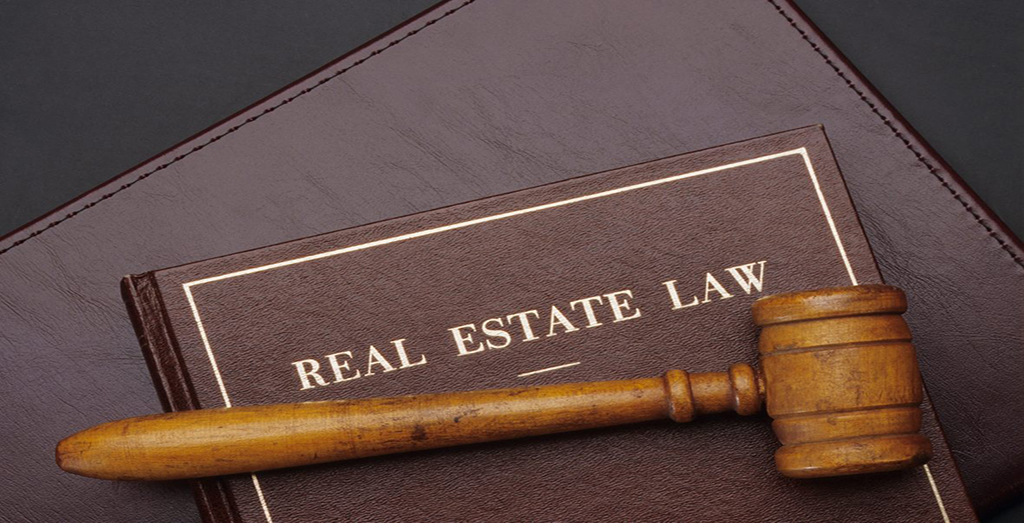Wooden gavel resting on a leather-bound Real Estate Law book
