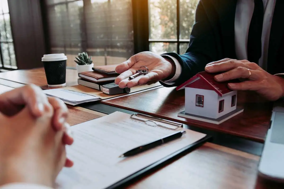 Real estate agent handing over house keys during a property purchase meeting